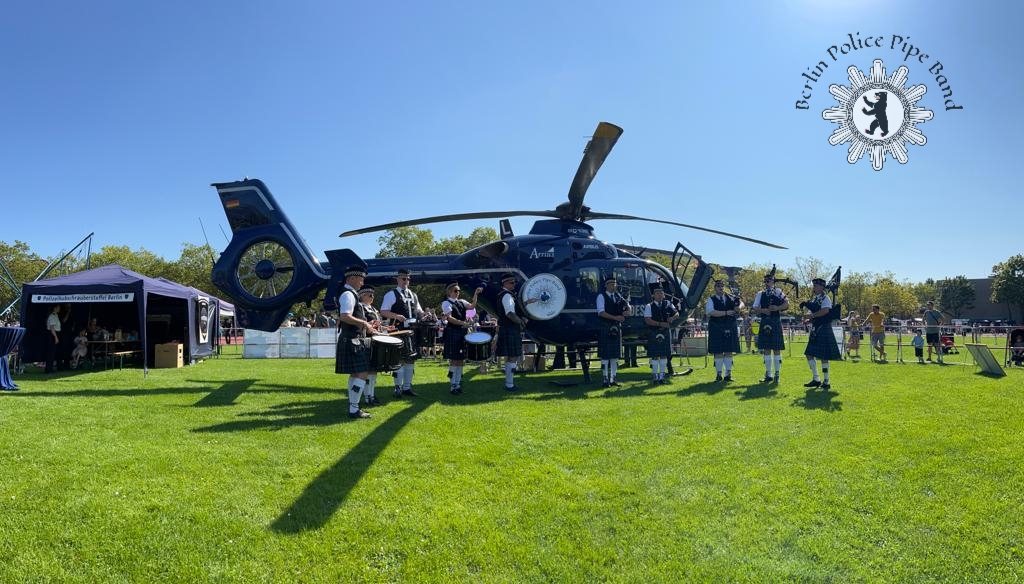 Die Berlin Police Pipe Band steht vor einem Polizeihelikopter