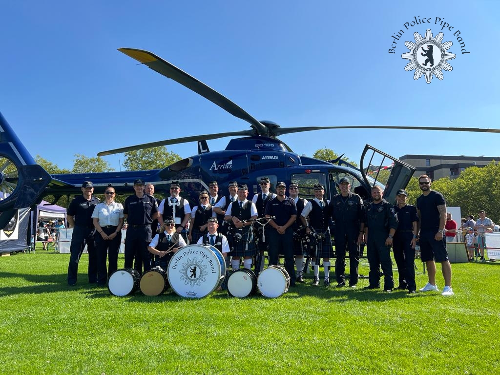 Die Band steht gemeinsam mit Polizistinnen und Polizisten vor dem Polizeihelikopter